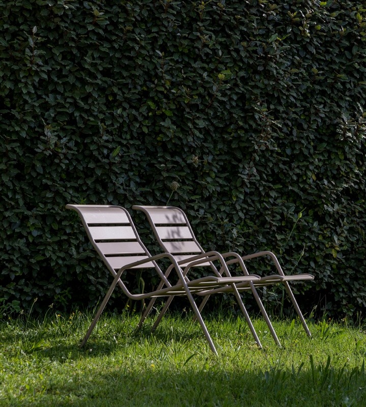 Chaises longues confortables dans un jardin verdoyant, entourées d'une haie dense, offrant une atmosphère paisible et relaxante, idéale pour profiter du calme de la nature. Parfaites pour les clients cherchant à se détendre dans un cadre naturel, en harmonie avec l'environnement serein de l'hôtel Lou Paradou.